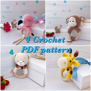 May include: Four crochet amigurumi patterns for baby rattles. The patterns include a pink flamingo, a brown monkey, a beige teddy bear, and a yellow giraffe. Each rattle is attached to a wooden ring.