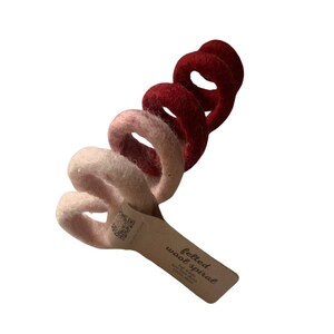 May include: A pink and red felted wool spiral. The spiral is made of several rings of wool that are felted together. The spiral is labeled "felted wool spiral".