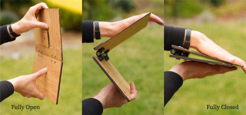May include: A wooden folding easel in three positions: fully open, partially open, and fully closed. The easel is made of light brown wood and has black metal hinges.