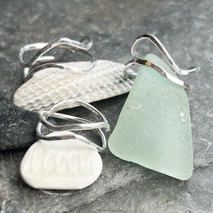 May include: Three silver rings with a wavy design. The rings are displayed on a white and grey background.