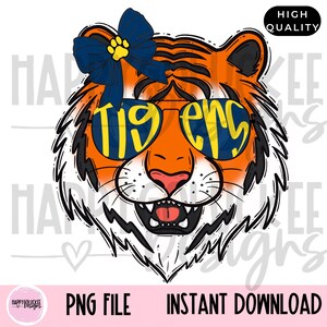 May include: A digital illustration of a tiger's face, featuring orange and black stripes, wearing sunglasses with the word "Tigers" in yellow. A blue bow with a yellow paw print is on the tiger's head. The image includes the text "PNG FILE" and "INSTANT DOWNLOAD".