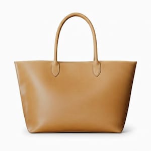 May include: A tan leather tote bag with two top handles. The bag has a rectangular shape with a flat base and a spacious interior. The handles are attached with small, rounded tabs. The bag is set against a white background.