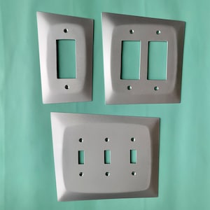 May include: Three silver metal light switch plates. The top plate has two switches, the middle plate has one switch, and the bottom plate has two switches.