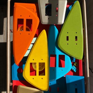 May include: A collection of assorted plastic light switch plates in various shapes and colours, including orange, yellow, lime green, blue, and beige. The plates feature rectangular and square cutouts for switches and mounting screw holes.