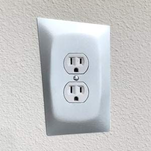 May include: A white electrical outlet with two standard outlets and a ground fault circuit interrupter (GFCI) button.