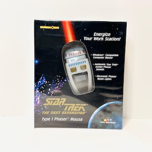Peut inclure: Souris Phaser Type 1 Star Trek: The Next Generation dans son emballage d'origine. La boîte présente le design de la souris, un faisceau laser rouge et le logo Star Trek. Elle est compatible Windows et émet des sons authentiques.