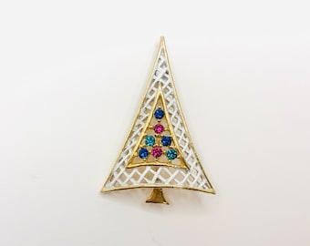 May include: A gold-tone Christmas tree brooch with a white enamel design and blue and pink rhinestones.