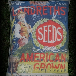 May include: Vintage pillow featuring a blue and yellow design with the text "Landreths Seeds American Grown" and a man holding a scythe. The text "Founded 1784" and "1899 115th Year" is also visible.