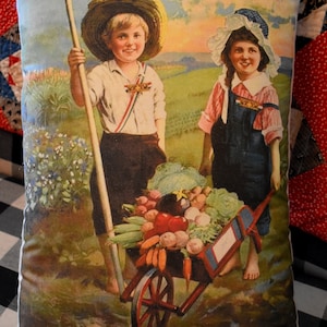 May include: A vintage pillow featuring a colorful illustration of two children in a garden. The boy is holding a rake and the girl is pushing a wheelbarrow full of vegetables. The text on the pillow reads "Helping Hoover in our U.S. School Garden."