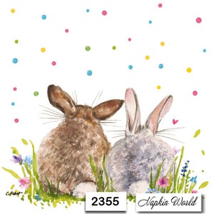 May include: Two brown and gray rabbits with fluffy tails are looking up at a shower of colorful confetti. The rabbits are surrounded by green grass and pink, purple, and blue flowers. The text "Napkin World" and "2355" are printed at the bottom of the image.
