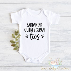 K&ouml;nnte beinhalten: Wei&szlig;er Baby-Strampler mit schwarzem Text, der "&iquest;ADIVINEN? QUI&Eacute;NES SER&Aacute;N =T&Iacute;OS=" lautet.