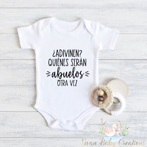 May include: White baby onesie with black text that reads: "¿ADIVINEN? QUIÉNES SERÁN =abuelos= OTRA VEZ"
