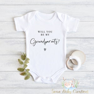 May include: White baby onesie with black text that reads "Will you be my grandparents?" with a small heart symbol below the text.