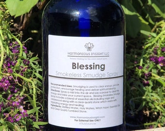 Può includere: Una bottiglia di vetro blu con un'etichetta bianca che recita "Blessing Smokeless Smudge Spray". L'etichetta include anche il testo "Harmonious Insight LLC" e "Solo per uso esterno".
