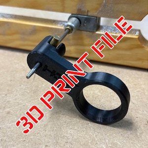 May include: A black 3D-printed tool with a circular handle and a projecting pin. The tool is connected to a metal rod and a wooden surface. The text "3D PRINT FILE" is printed in red diagonally across the image.