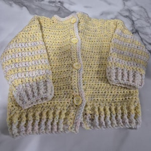 Hand crocheted, unisex toddler&#39;s cardigan in sunshine yellow and white tones sized to fit 12 months to 2 years old.