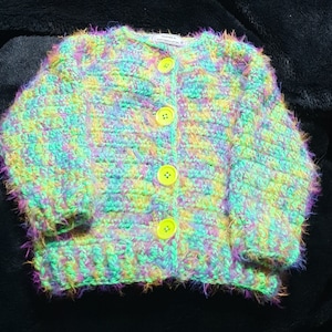 Extra soft, hand crocheted, unisex toddler&#39;s cardigan in green and rainbow tones sized to fit 18 months to 3 years old.