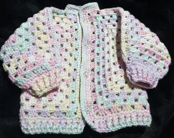 Soft pastel, rainbow toned, unisex, baby cardigan sized to fit a newborn to 3 months.