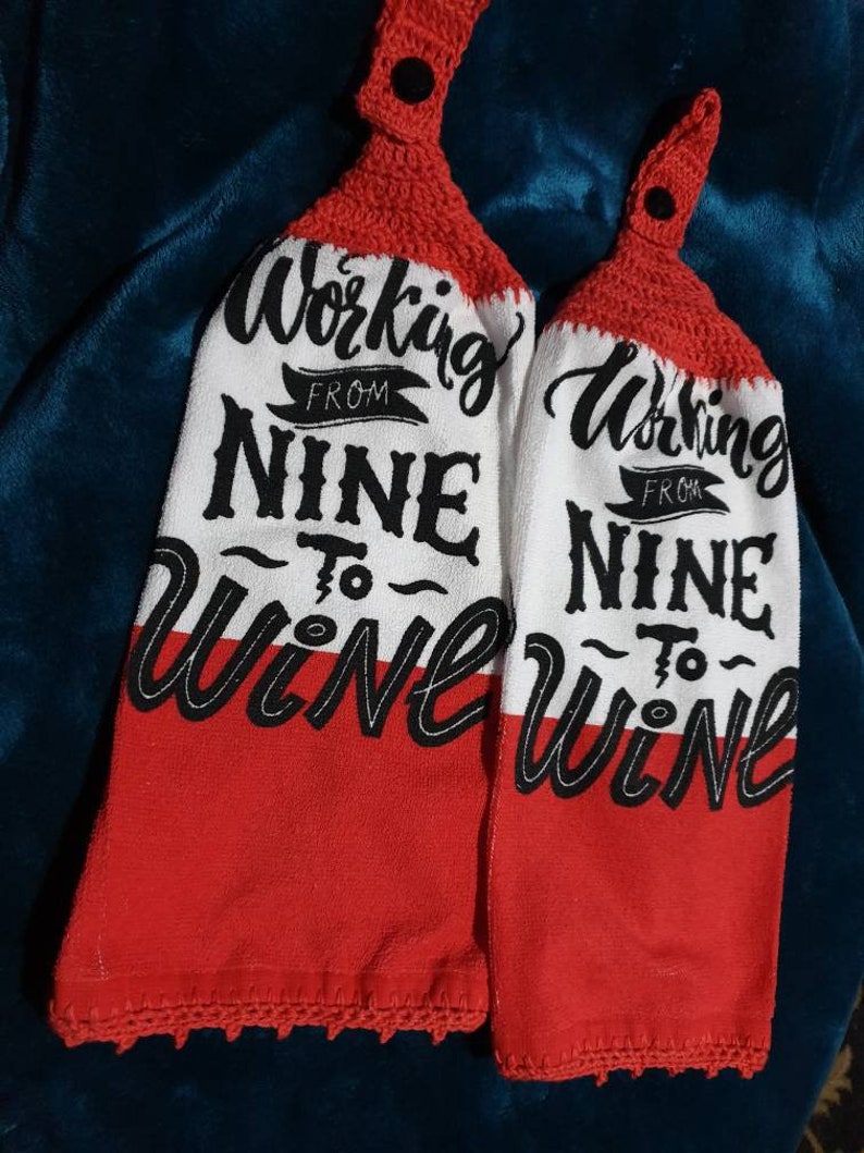 May include: Two white and red kitchen towels with the text "Working From Nine To Wine" in black script. The top portion is red crochet with a black button. The bottom half of the towels are red.