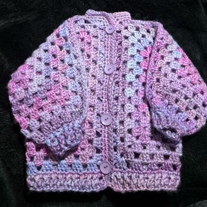 Hand crocheted, easy care acrylic baby or toddler cardigan in pink and mauve tones sized to fit 9 to 18 months old.
