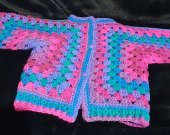 Hand made winter cardigan from toddler aged 2 years plus in purple, magenta, green and blue easycare acrylic yarn.