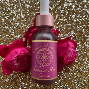 May include: A small glass bottle with a dropper top, filled with a pink liquid. The bottle has a label that reads "Cosmic Alignment Lokelani Rose Glycerite" with a pink and gold geometric design.