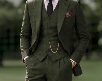 Könnte beinhalten: Ein dreiteiliger olivgrüner Anzug bestehend aus einem strukturierten Blazer, einer passenden Weste mit goldener Taschenuhrkette und einer Hose. Das Ensemble umfasst ein weißes Hemd mit Kragen, eine schwarze Krawatte und ein dunkles Einstecktuch.