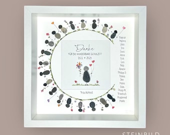 May include: A white frame with a circle of gray stones representing children. The stones are holding hands and have small flowers drawn on them. Inside the circle is a white card with the text "Danke für die wunderbare Schulzeit 2022 - 2025" and a drawing of a person holding flowers. The text "Frau Kohtell" is below the drawing. The frame has the text "STEINBILD MANUFAKTUR" at the bottom.