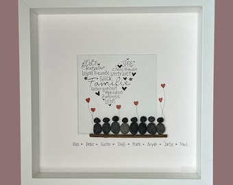 May include: A square white framed wall art piece featuring a heart-shaped word cloud in black ink with German text, eight grey pebble figures standing on a wooden strip, red painted heart balloons, and the names Elke, Peter, Günter, Steffi, Malte, Aliyah, Jantje, Paul.