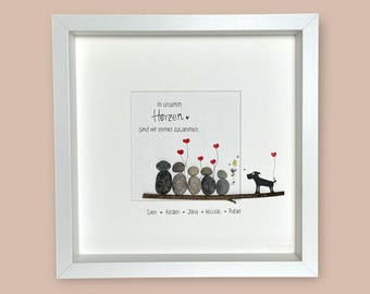 May include: A white framed picture with a black and white pebble art design of a family of five and a dog. The text in the picture reads "In unseren Herzen Sind wir immer zusammen" with the names Sven, Kirsten, Jana, Nicolas, and Rafael below the pebble art.