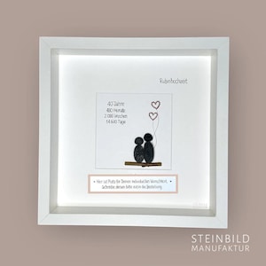 Può includere: Una cornice bianca con una luce all'interno, che mostra un'opera d'arte in pietra di due figure sedute su un ramo con tre cuori rossi che galleggiano sopra di loro. Il testo "40 Jahre, 480 Monate, 2.086 Wochen, 14.600 Tage" e "Rubinhochzeit" è visibile nell'immagine. Il testo "Hier ist Platz für Deinen individuellen Wunschtext. Schreibe diesen bitte mit in die Bestellung." è anche visibile nell'immagine.