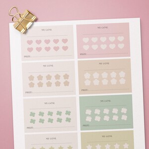 May include: A planner sheet with pastel-coloured boxes for tracking goals. Each box has the words "MY GOAL" and "PRIZE:" above and below rows of hearts, flowers, butterflies, and stars. A gold paper clip is in the upper left corner.
