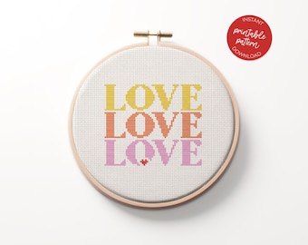 May include: A cross-stitch pattern featuring the word "LOVE" repeated three times in a stacked design. The word "LOVE" is in yellow, orange, and pink.