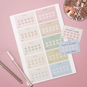 May include: A sheet of goal-setting cards with pastel-coloured squares, each featuring a different shape like hearts, stars, and flowers. Two pens and a container of office supplies are also visible. The cards have the words "My Goal" and "Prize".