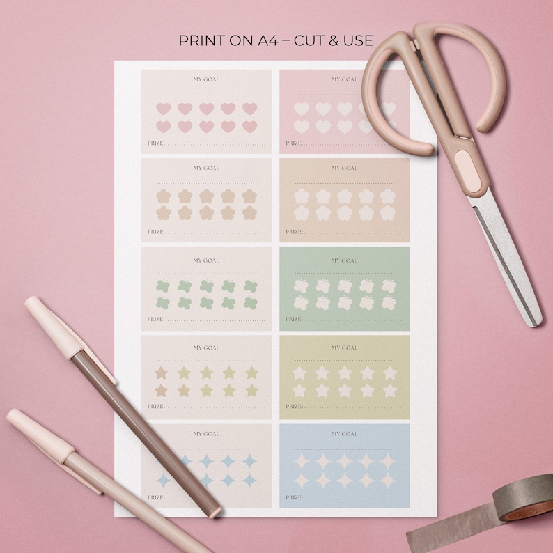 May include: A printed A4 sheet with goal-tracking charts, each with a different shape: hearts, flowers, butterflies, stars, and diamonds. The text "PRINT ON A4 - CUT & USE" is at the top. A pair of scissors, two pens, and a roll of tape are also visible.