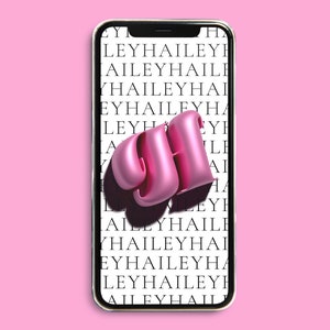 Puede incluir: Un teléfono inteligente con un "GH" en 3D rosa en la pantalla. El fondo de la pantalla es un patrón repetitivo de la palabra "HAILEY" en texto negro.