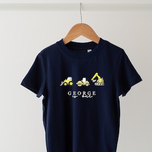 Peut inclure: Un t-shirt bleu marine avec un motif de véhicules de chantier et le texte "GEORGE is one".