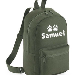 May include: A green canvas backpack with a white paw print design and the name "Samuel" printed on the front.