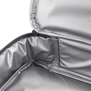 May include: The inside of a silver insulated lunch bag with a zipper closure. The bag has a small pocket on the inside.