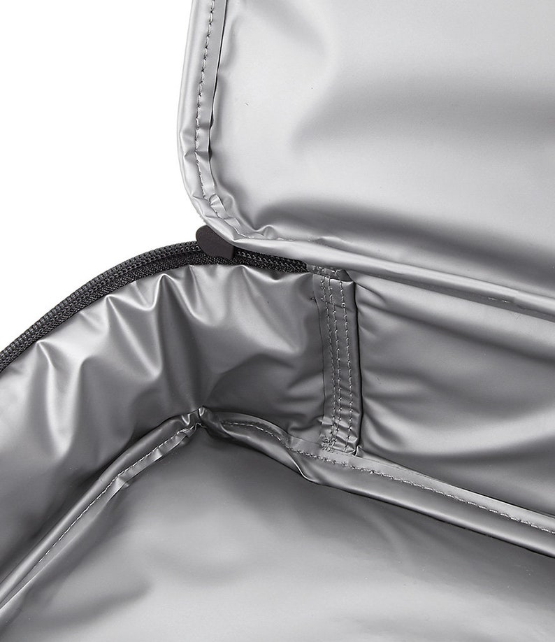 May include: The inside of a silver insulated lunch bag with a zipper closure. The bag has a small pocket on the inside.