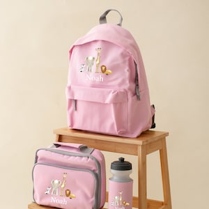 May include: Pink personalized backpack, lunch bag, and water bottle set with a safari animal theme. The set features a giraffe, elephant, lion, and zebra. The name "Noah" is embroidered on each item.