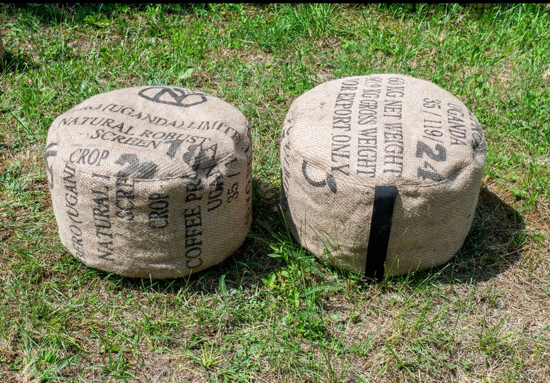 May include: Two brown burlap bean bags with black straps. The bean bags are labeled with black text that reads "UGANDA 35/119/24 60KG NET WEIGHT KG GROSS WEIGHT FOR EXPORT ONLY" and "(UGANDA) LIMITED NATURAL ROBUST SCREEN CROP COFFEE PRODUCE UG 35/119/24".