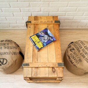 May include: A wooden crate with a comic book titled "Borderlands: Pre-Sequel" on top. Two burlap sacks with text printed on them are on either side of the crate.