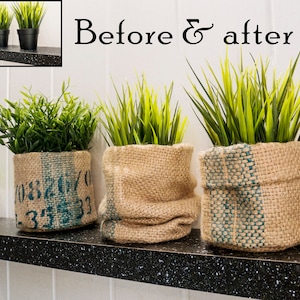 Könnte beinhalten: Drei Topfpflanzen mit grünen Blättern in Jutesäcken auf einem schwarzen Regal. Die Töpfe haben einen rustikalen Look und sind eine großartige Möglichkeit, jedem Raum einen Hauch von Natur zu verleihen.