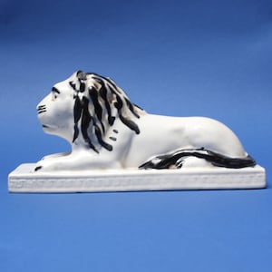 Lion. White Lion, an old, rustic ceramic figurine, handmade and painted. Lion on a pedestal with a Greek ornament (meander)