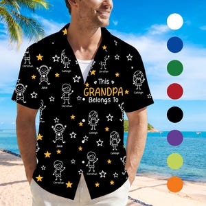 May include: Black short-sleeved shirt with a white undershirt. The shirt has a repeating pattern of stick figures, stars, and the text "This Grandpa Belongs To." Names are printed above the stick figures. The shirt is a button-down style.