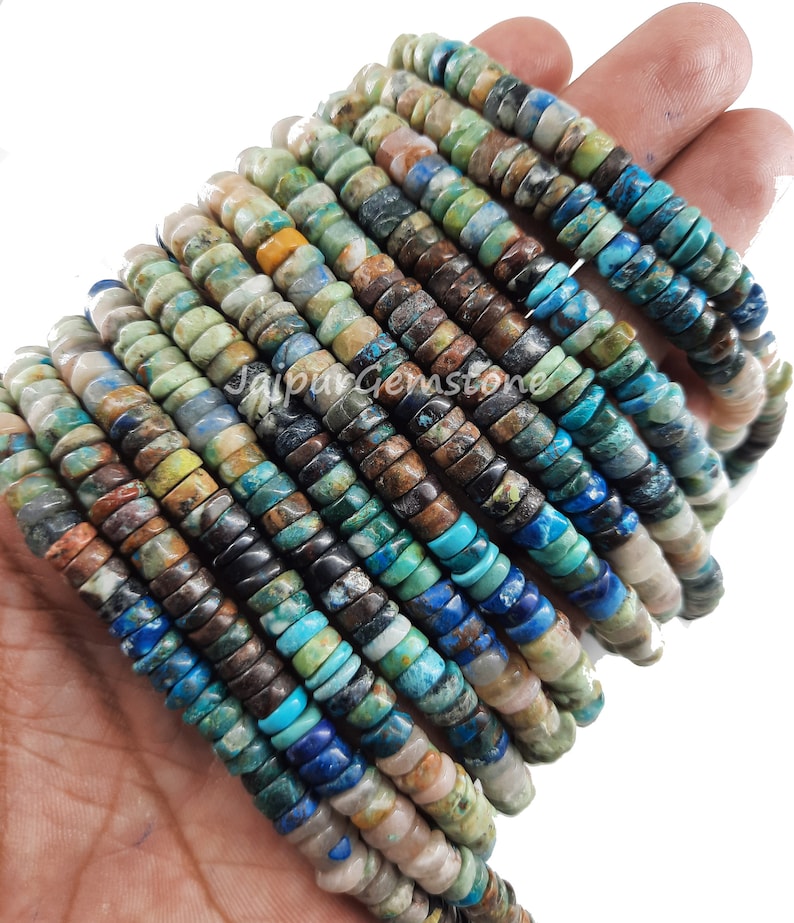 May include: A strand of turquoise gemstone beads, featuring a mix of blue, green, brown, and white colors. The beads are round and have a smooth, polished finish.