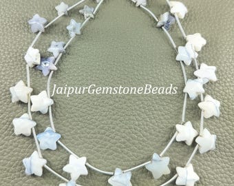 May include: Two strands of star-shaped beads in white and blue hues. The beads are strung on silver wire, arranged symmetrically. The text "JaipurGemstoneBeads" is visible. The beads are likely for jewellery making.