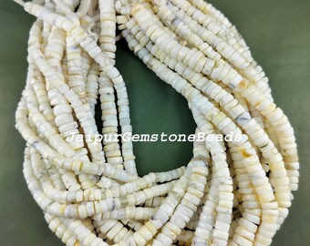 May include: A strand of white shell beads with a slight iridescent sheen. The beads are small and round, and they are strung on a white cord. The beads are arranged in a loose, flowing pattern. The text "JaipurGemstoneBeads" is visible in the center of the image.