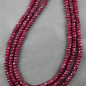 Puede incluir: Un collar de cuentas de rub&iacute; rojo oscuro, facetadas y enhebradas en tres filas.
